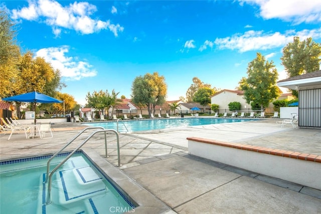 community pool with a patio area and fence