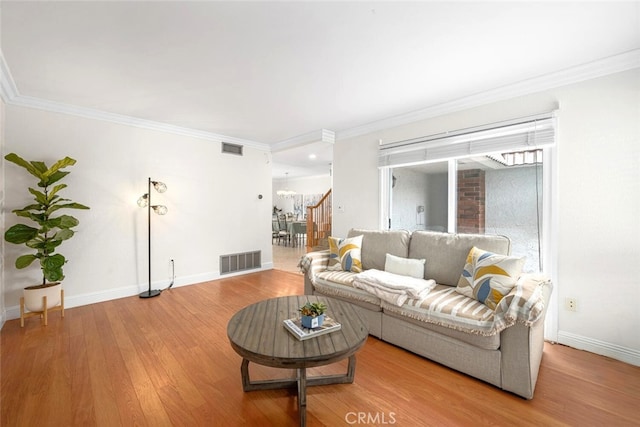 living room featuring wood finished floors, visible vents, ornamental molding, and baseboards