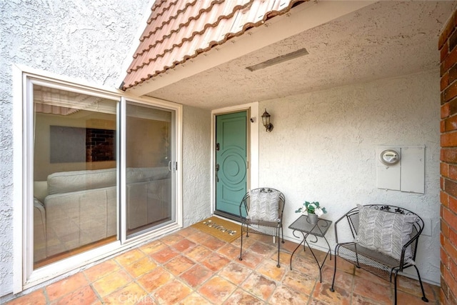 doorway to property with stucco siding, a patio, and a tile roof