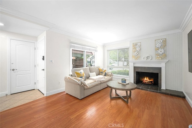 living area with baseboards, ornamental molding, wood finished floors, and a fireplace