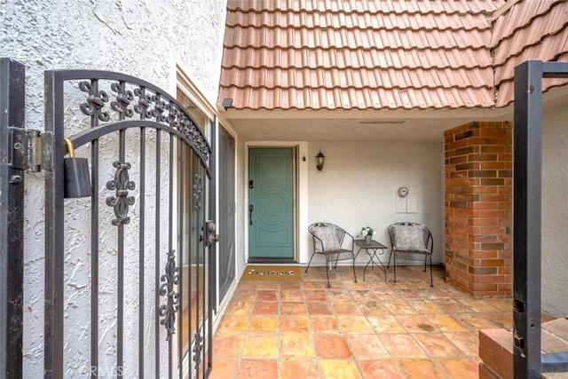 property entrance featuring stucco siding, a gate, and a tile roof