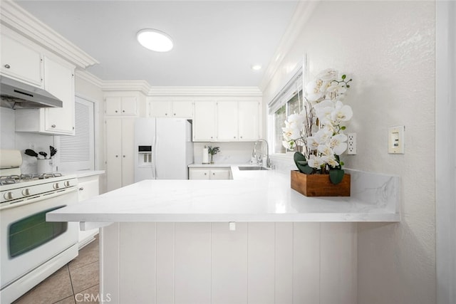 kitchen featuring a sink, under cabinet range hood, white appliances, a peninsula, and light countertops