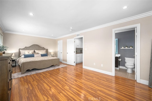 bedroom featuring crown molding, light wood-style flooring, connected bathroom, and baseboards