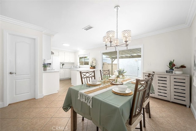 dining room with light tile patterned floors, ornamental molding, and an inviting chandelier