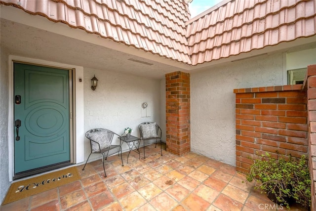 view of exterior entry featuring stucco siding and a tiled roof