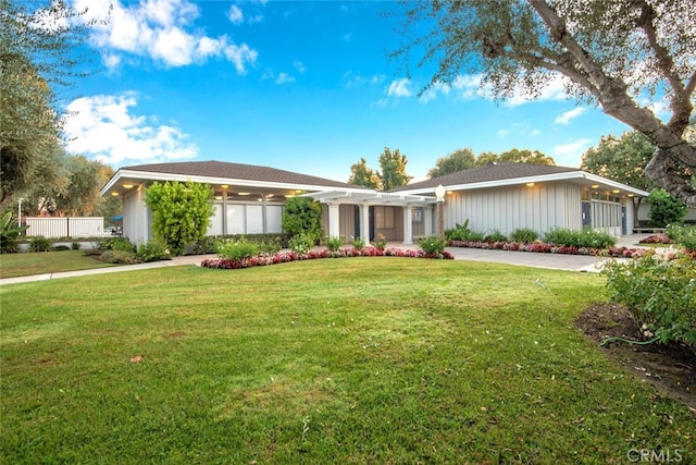 ranch-style home with a pergola, a front yard, and board and batten siding