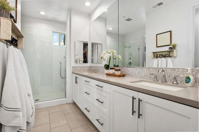 bathroom featuring a sink, visible vents, backsplash, a shower stall, and tile patterned floors