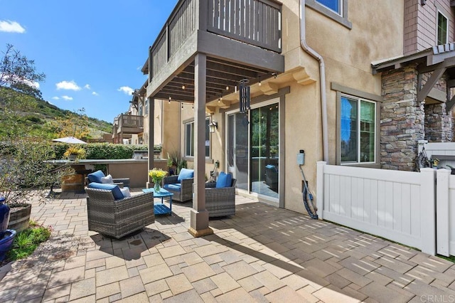 view of patio / terrace with a balcony, fence, and an outdoor hangout area