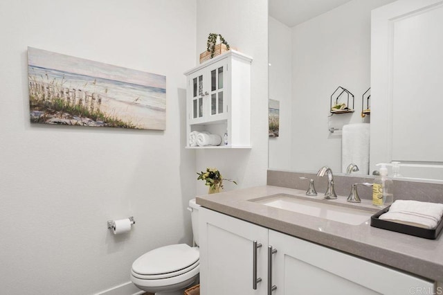 half bath with toilet, baseboards, and vanity