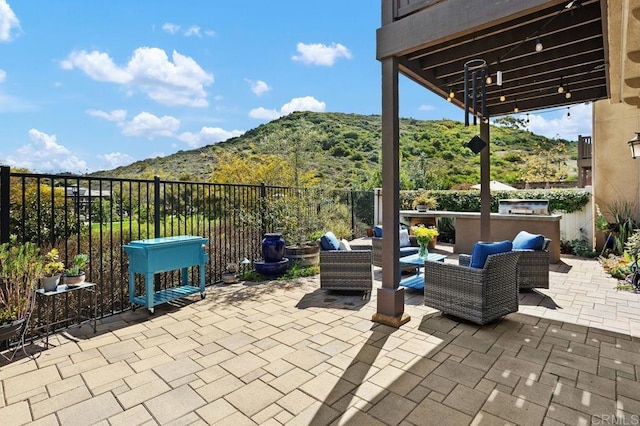 view of patio / terrace featuring a mountain view, fence, and an outdoor living space