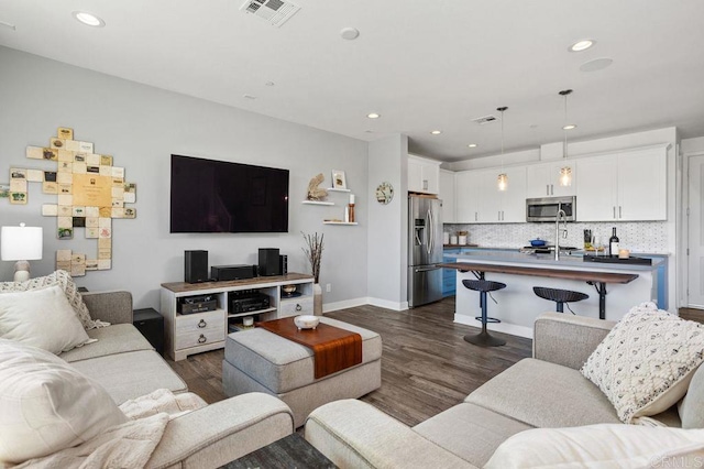 living area featuring baseboards, dark wood-style flooring, visible vents, and recessed lighting