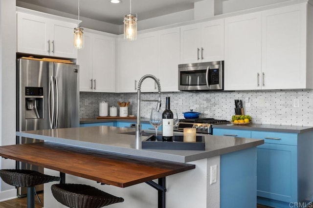 kitchen with stainless steel appliances, hanging light fixtures, backsplash, and white cabinetry