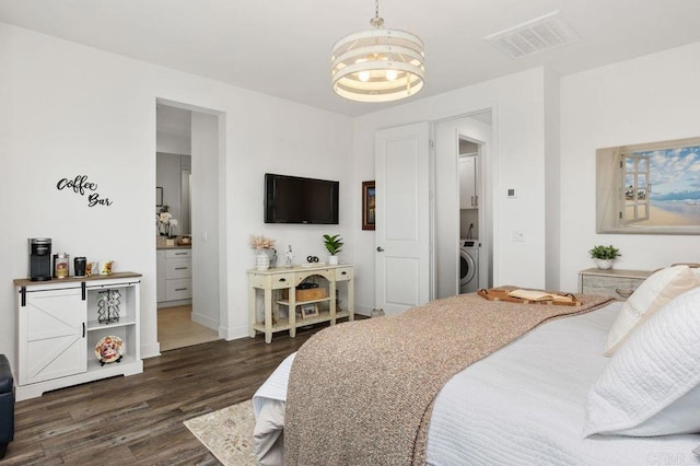 bedroom with a notable chandelier, washer / clothes dryer, visible vents, dark wood-type flooring, and baseboards