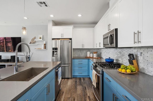 kitchen featuring stainless steel appliances, a sink, visible vents, blue cabinetry, and dark countertops