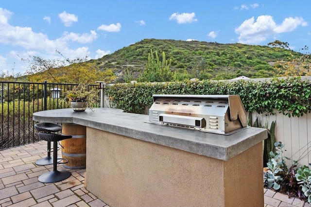 view of patio / terrace featuring a grill, fence, and an outdoor kitchen