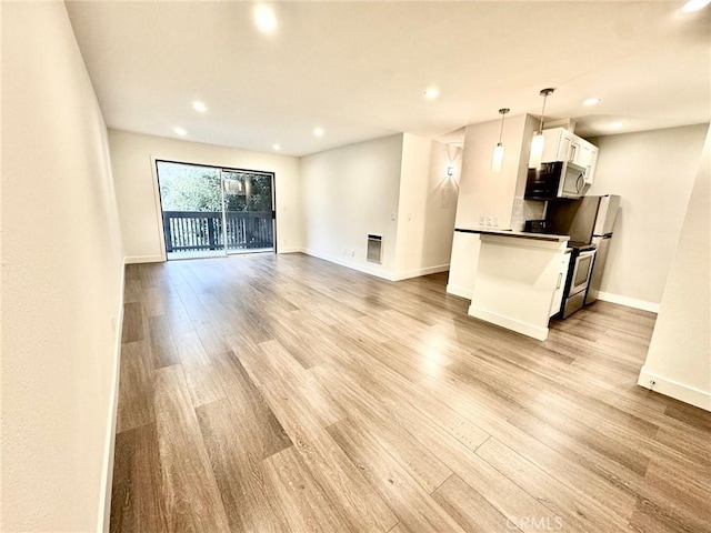 unfurnished living room with recessed lighting, baseboards, and light wood-type flooring