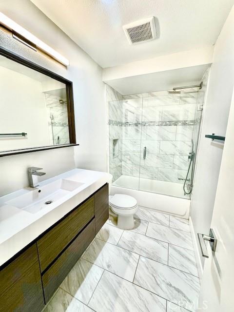 bathroom with toilet, visible vents, marble finish floor, and enclosed tub / shower combo