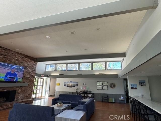 living area featuring wainscoting, a brick fireplace, a high ceiling, and wood finished floors