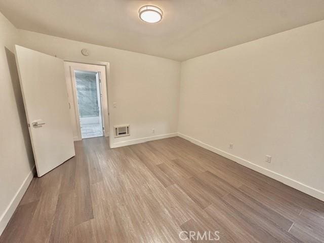 spare room featuring baseboards and wood finished floors