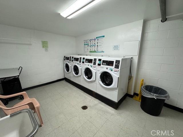 community laundry room with light floors and concrete block wall