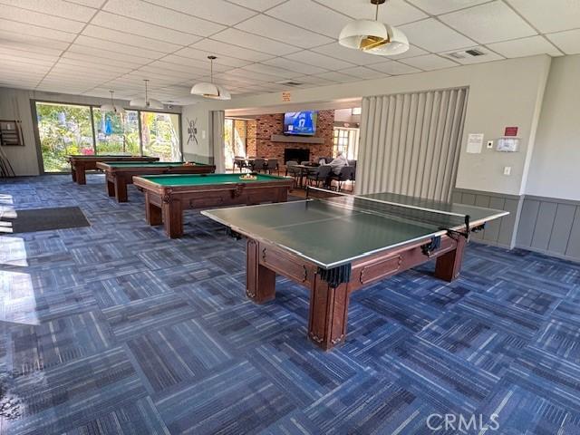 recreation room featuring visible vents, a drop ceiling, wainscoting, a fireplace, and pool table