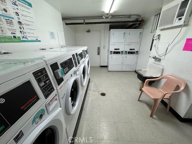 common laundry area featuring independent washer and dryer, a wall mounted AC, light floors, and stacked washer and dryer