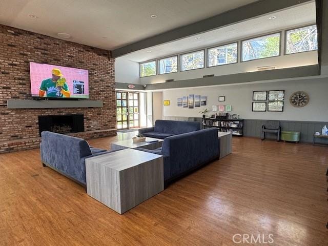 living area featuring beamed ceiling, brick wall, and wood finished floors