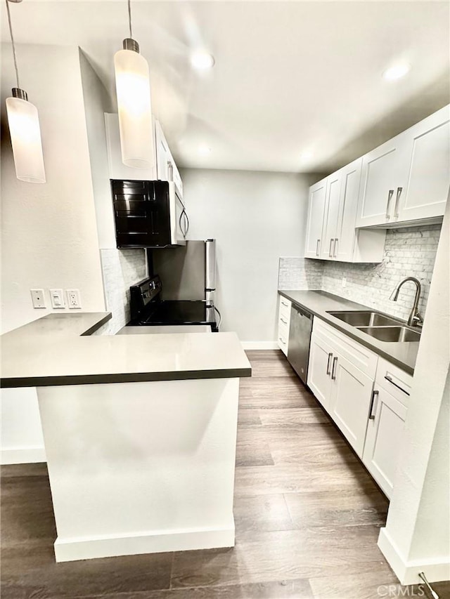 kitchen featuring a sink, tasteful backsplash, appliances with stainless steel finishes, a peninsula, and dark wood-style flooring