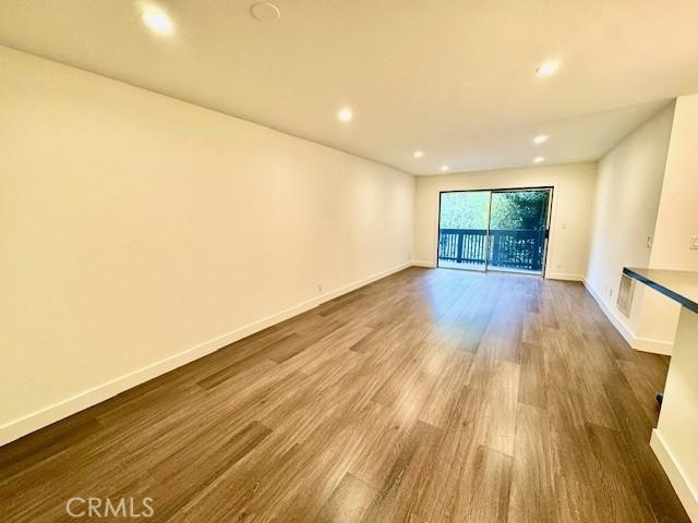 spare room featuring recessed lighting, wood finished floors, and baseboards