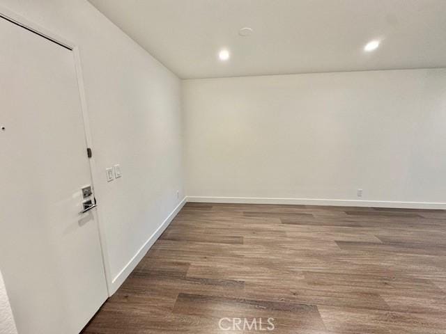 spare room featuring recessed lighting, wood finished floors, and baseboards