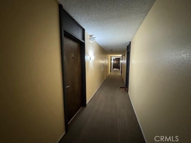 hall with baseboards, a textured ceiling, and dark wood finished floors