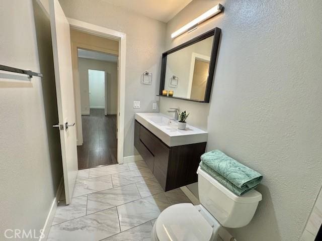 3601 W Hidden Ln Unit 309, Rolling Hills Estates, CA 90274 - bathroom featuring marble finish floors, toilet, vanity, a textured wall, and baseboards