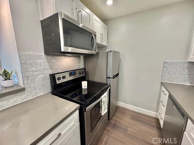 3601 W Hidden Ln Unit 309, Rolling Hills Estates, CA 90274 - kitchen featuring appliances with stainless steel finishes, decorative backsplash, dark wood finished floors, and white cabinets