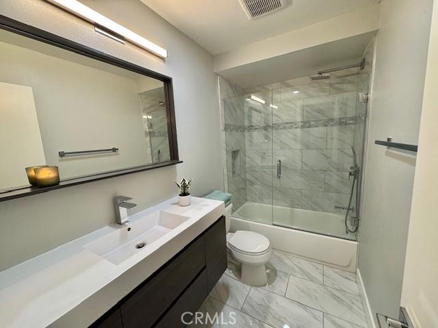 3601 W Hidden Ln Unit 309, Rolling Hills Estates, CA 90274 - bathroom featuring marble finish floors, vanity, shower / bath combination with glass door, toilet, and baseboards