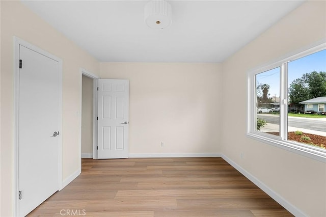 empty room featuring light wood-type flooring and baseboards