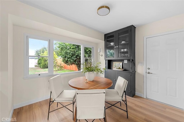 dining space featuring baseboards, plenty of natural light, and light wood finished floors