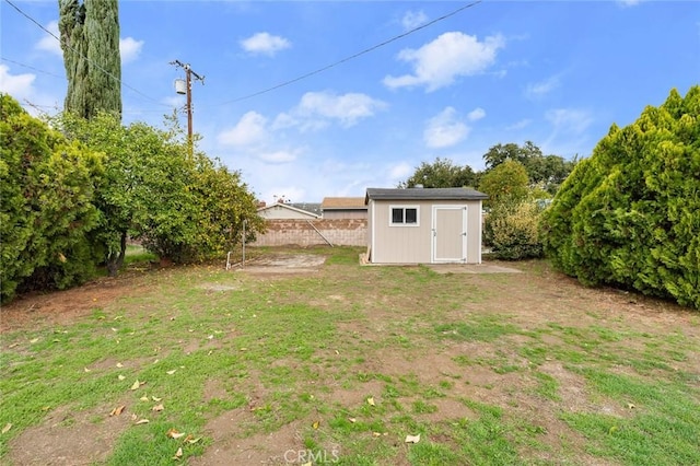 view of yard featuring a storage unit, an outdoor structure, and fence