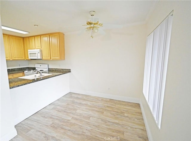 kitchen with white appliances, light wood finished floors, baseboards, dark countertops, and light brown cabinets