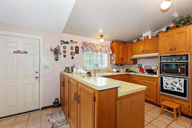 kitchen with a sink, gas stovetop, a peninsula, light countertops, and lofted ceiling