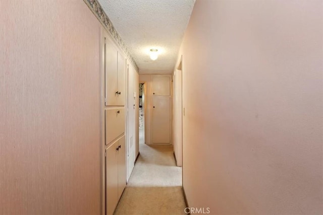 hallway featuring light carpet and a textured ceiling