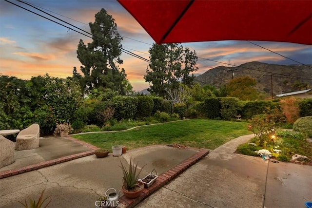 yard at dusk featuring a mountain view and a patio