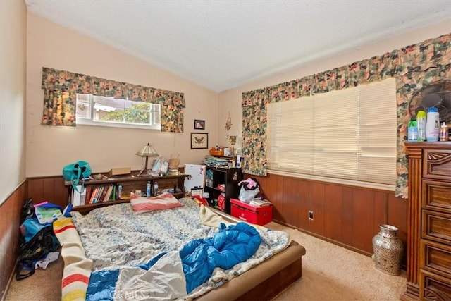 carpeted bedroom with lofted ceiling, wooden walls, wainscoting, and a textured ceiling