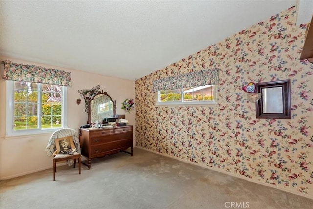 living area with lofted ceiling, a textured ceiling, carpet flooring, wallpapered walls, and baseboards