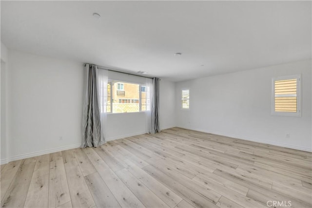 spare room featuring light wood-style floors and baseboards