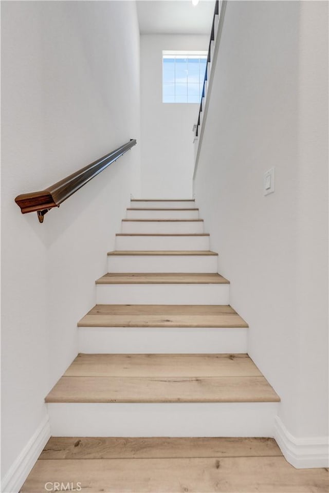 staircase with baseboards and wood finished floors