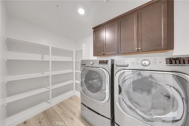 clothes washing area with light wood-type flooring, washer and dryer, cabinet space, and recessed lighting