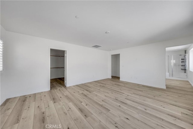 empty room with visible vents, light wood-style flooring, and baseboards