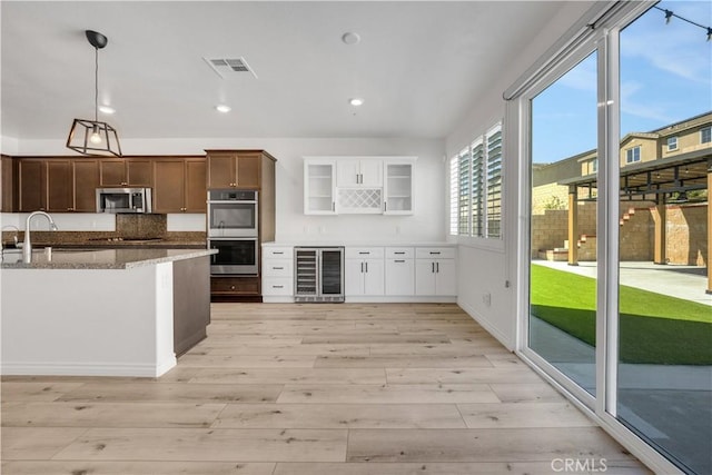 kitchen featuring beverage cooler, a sink, visible vents, appliances with stainless steel finishes, and light wood finished floors