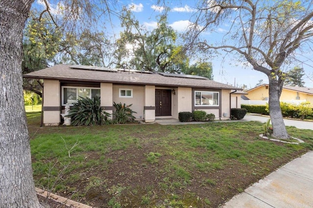 ranch-style house featuring a front yard, solar panels, and stucco siding