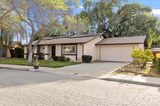 single story home with stucco siding, an attached garage, roof mounted solar panels, driveway, and a front lawn